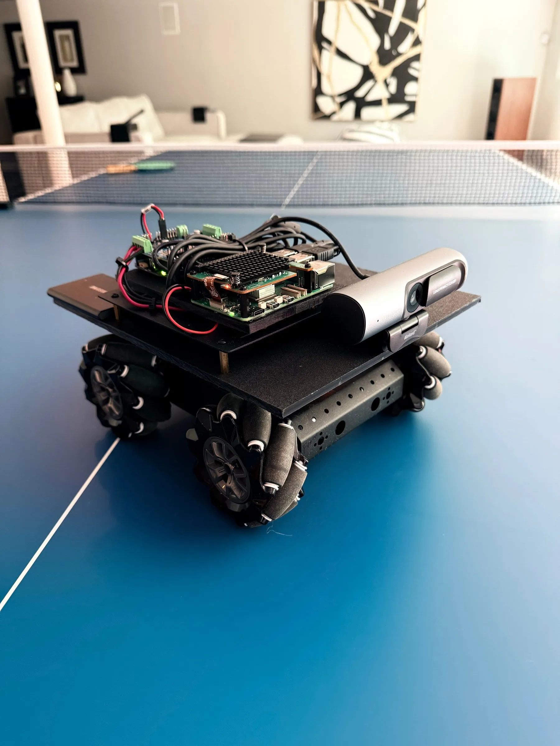 The rover on the workbench — mecanum wheels, onboard compute, and a camera bar